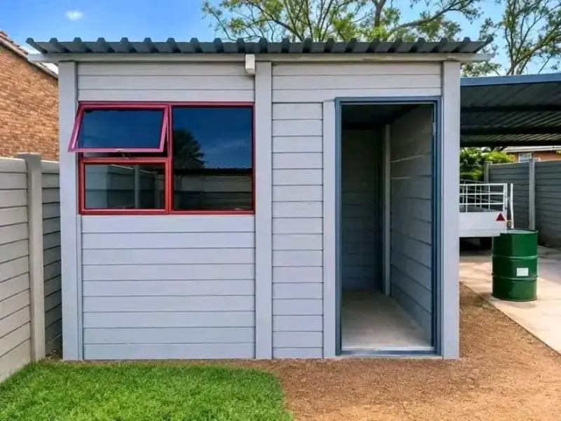 Grey precast room with red-framed window and open door